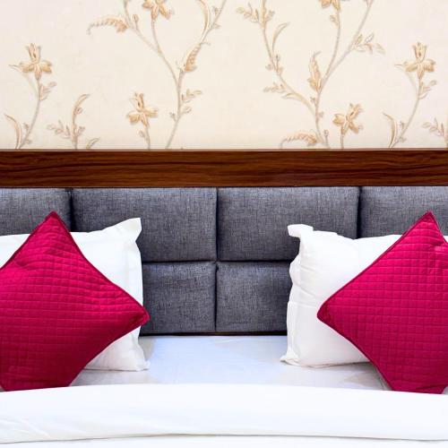 a bedroom with red and white pillows on a bed at Hotel Om Palace in Mathura