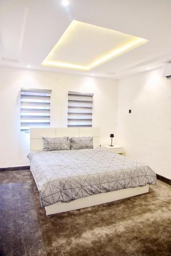 a white bedroom with a bed and two windows at THE NEST by CHECKLIST in Pakuro