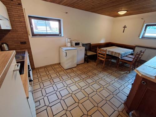 a kitchen with a refrigerator and a table with a cross on the wall at Haus mit zwei Ferienwohnungen in Boxtal