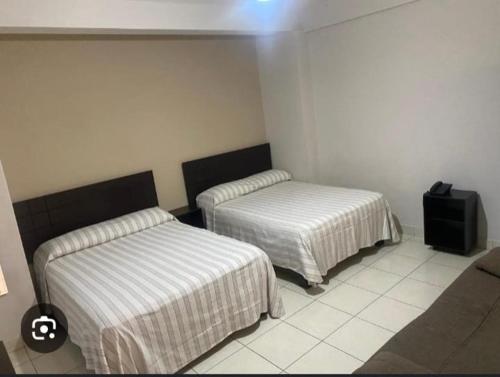 a room with two beds and a television in it at Hotel Bamboo Sauces Morelia in Morelia