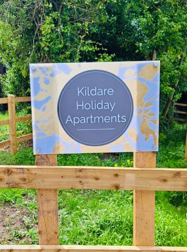 a sign on a wooden fence in a garden at Kildare Holiday Apartments No 3 in Kildare