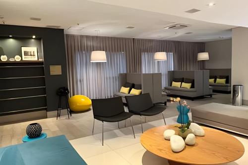 uma sala de estar com um sofá, uma mesa e cadeiras em Suíte em flat no Gonzaga Stay Helbor em Santos