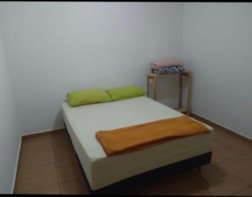 ein kleines Schlafzimmer mit einem Bett mit weißer Bettwäsche und grünen Kissen in der Unterkunft Recanto da Celinha - Casa em Tiradentes in Tiradentes