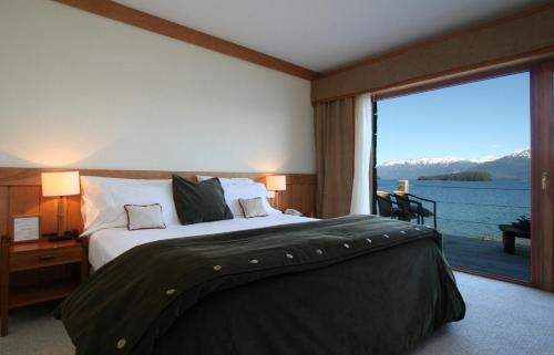 a bedroom with a large bed and a large window at Correntoso Lake & River Hotel in Villa La Angostura