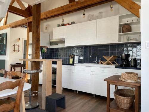 une cuisine avec des armoires blanches et une table dans l'établissement ancienne poste de Saint coulomb, à Saint-Coulomb