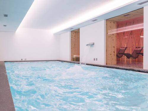 an indoor swimming pool with blue water in a room at Residence Adamello Resort in Ponte di Legno