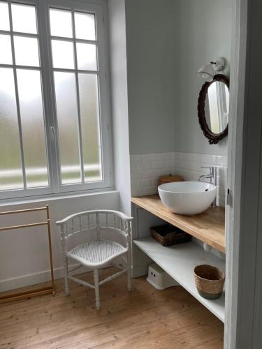 une salle de bain avec un lavabo, un miroir et une chaise dans l'établissement ancienne poste de Saint coulomb, à Saint-Coulomb
