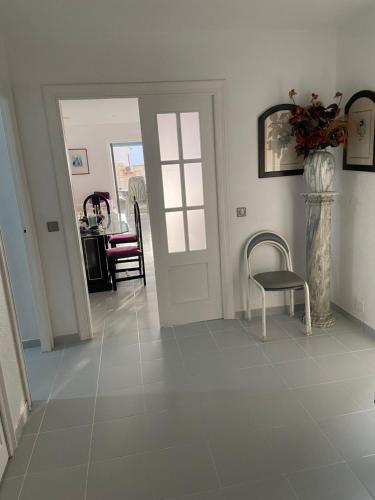 a hallway with a tile floor with a chair and a door at Residencial Aguilas Playa in Águilas