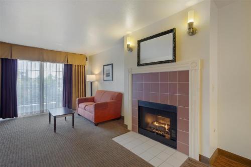 a living room with a fireplace and a red chair at Best Western Luxury Inn in Tracy