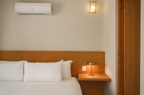 a hotel room with a bed and a lamp on a table at Cholula Condesa Hotel by Lumina in Mexico City
