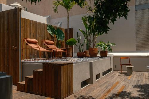 a lobby with a counter with chairs and plants at Cholula Condesa Hotel by Lumina in Mexico City