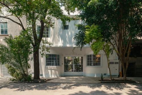 a white building with trees in front of it at Cholula Condesa Hotel by Lumina in Mexico City