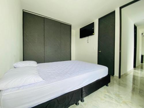 a bedroom with a large white bed with a black headboard at Apartamento Conjunto Altos de Laureles in Melgar
