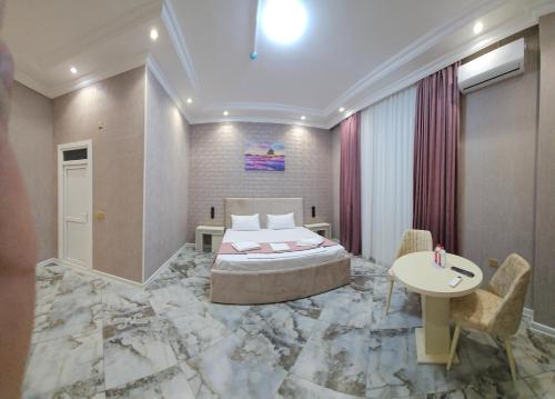 a hotel room with a king sized bed and a table at Kolizey Hotel Spa Ganja in Ganja
