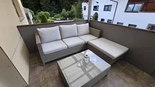 a patio with a couch and a table on a balcony at AlpenRide Ski & Bike Urlaub in Fliess