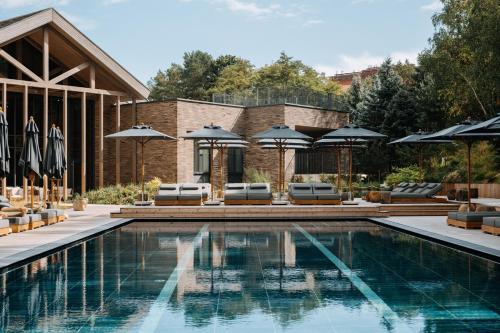 a swimming pool with umbrellas and chairs and a house at Golden Dunes & SPA in Nida