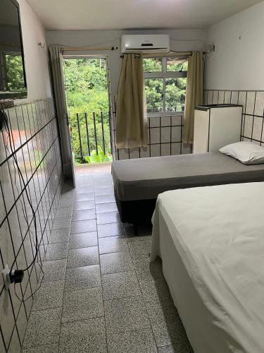 a bedroom with two beds and a door with a window at Hotel Cascata in Tianguá