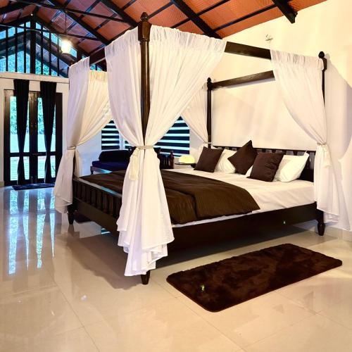 a bedroom with a canopy bed with curtains and a rug at Coorg Robusta Retreat in Suntikoppa