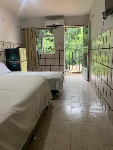 a hotel room with two beds and a balcony at Hotel Cascata in Tianguá