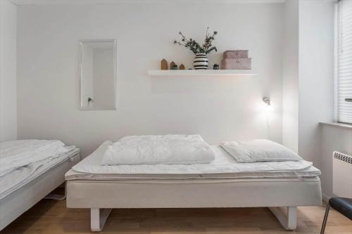 a white bedroom with two beds and a shelf at M361-Vaeggerlose-Marielyst-Strandvej-63-U in Marielyst