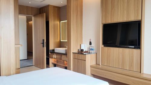 a bedroom with a bed and a television and a sink at WeLight Hotel in Beijing
