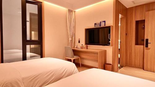 a hotel room with a bed and a desk with a television at WeLight Hotel in Beijing