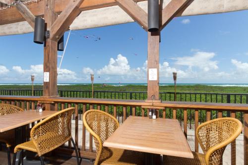 two tables and chairs on a deck with a view of the ocean at Palms Resort & Cafe on the Beach in South Padre Island