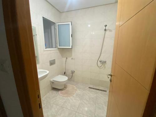 a white bathroom with a toilet and a window at Résidence flaurence la marsa in El Haouach