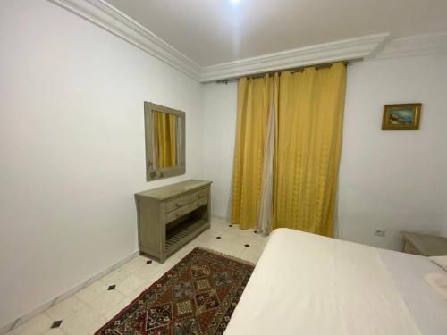 a bedroom with a bed and a dresser and a mirror at Résidence flaurence la marsa in El Haouach