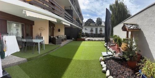 a backyard with green grass and a dining area at Charmant appartement, hyper central, à 2 min de tout, énorme terrasse privée et parking couvert in Crans-Montana