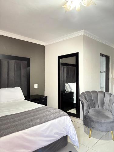 a bedroom with a bed and a chair and a mirror at Nyakhosi Luxury Guesthouse in Thohoyandou