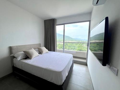a bedroom with a bed and a large window at Apartamento familiar en Santa Marta con vista al mar y la Sierra in Santa Marta