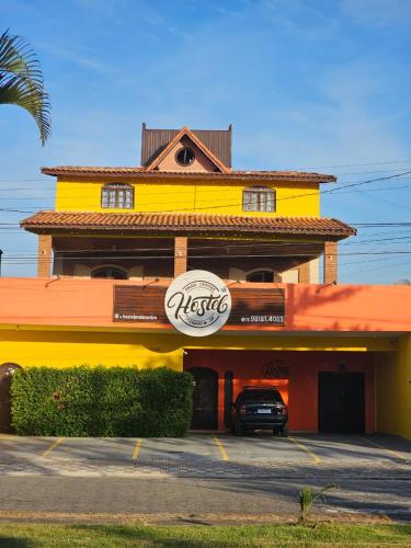 a yellow and orange building with a car parked outside at Hostel Praia Centro Itanhaém in Itanhaém