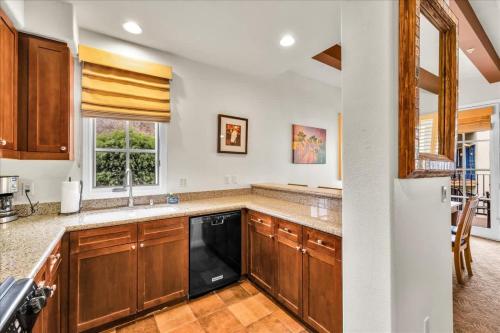 a kitchen with wooden cabinets and a black dishwasher at Spectacular Desert Retreat in La Quinta #A in La Quinta