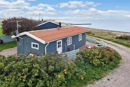 a blue house with a red roof next to the ocean at SL190-Korsor-Svenstrup-Strandvej-103 in Korsør