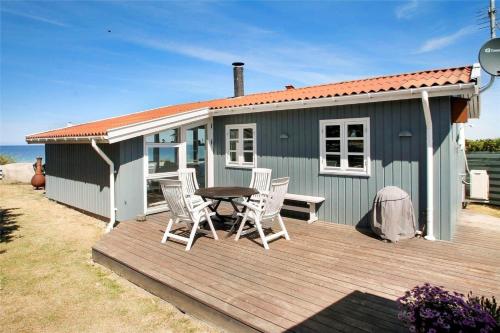 a blue house with a table and chairs on a deck at SL190-Korsor-Svenstrup-Strandvej-103 in Korsør