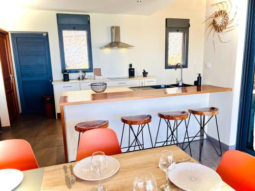 - une cuisine avec un bar avec des chaises orange et une table dans l'établissement Comme un bateau sur l'océan, à Saint-Leu