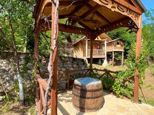 a wooden gazebo with a barrel and a house at Gentry House in Ambrolauri