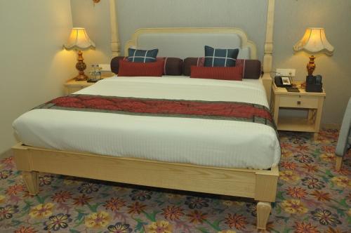 a bedroom with a large bed with two night stands at Royal Tulip Navi Mumbai in Navi Mumbai