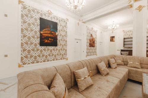 a living room with a large couch and a chandelier at Kolizey Hotel Spa Ganja in Ganja