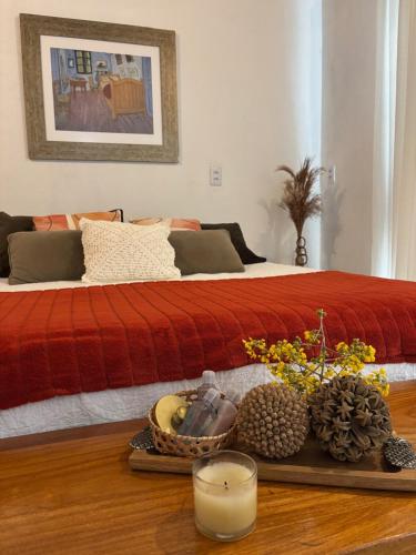 a bed with a red blanket and a table with a candle at Casa Cobogó in Cavalcante