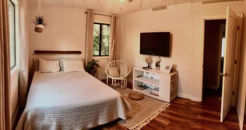 a bedroom with a white bed and a television at Entire home in Athens, Georgia with Piano in Athens