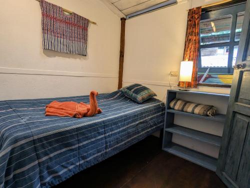 a bedroom with a bed with an orange robe on it at La Iguana Perdida in Santa Cruz La Laguna
