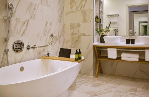 a white bath tub in a bathroom with a sink at The Posthouse Berlin Potsdamer Platz- Leonardo Limited Edition in Berlin
