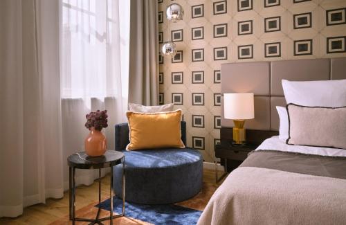 a bedroom with a bed and a chair next to a window at The Posthouse Berlin Potsdamer Platz- Leonardo Limited Edition in Berlin