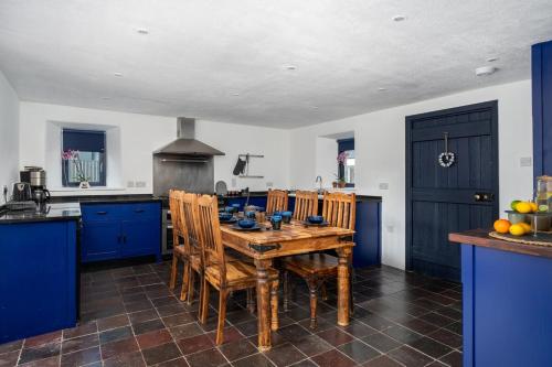 a kitchen with a wooden table and blue cabinets at Charming Country house Getaway in Edenderry