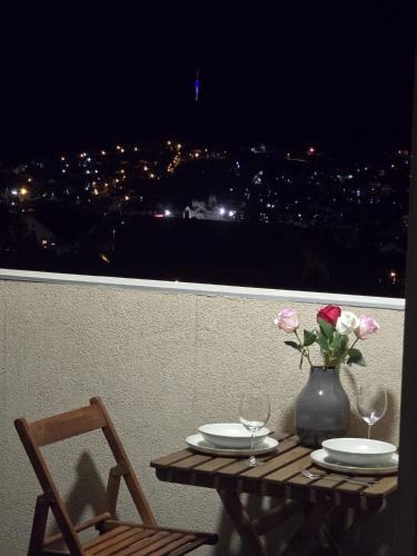 Una mesa con un jarrón de flores en un balcón. en Apartman Emi, en Belgrado
