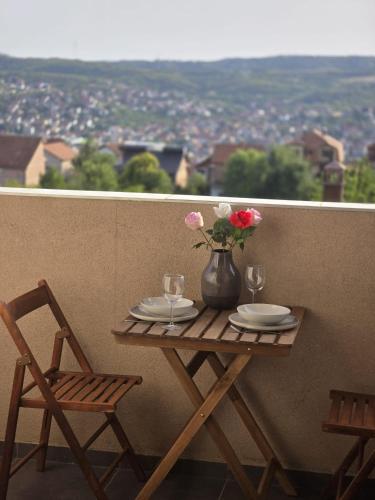 una mesa con platos y un jarrón con flores en el balcón en Apartman Emi, en Belgrado