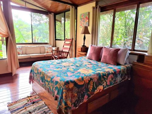 ein Schlafzimmer mit einem Bett in einem Zimmer mit Fenstern in der Unterkunft Eden Atenas Costa Rica in Atenas