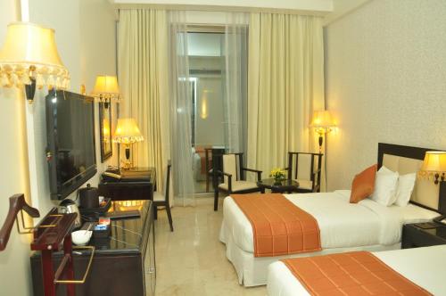 a hotel room with two beds and a television at Royal Tulip Navi Mumbai in Navi Mumbai